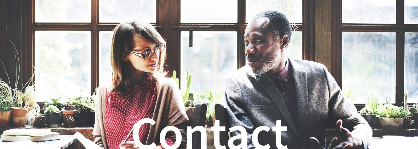 banner for Contact page, 2 individuals chatting in a warmly lit space