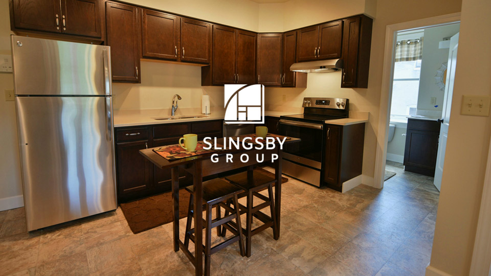 Portfolio image: photography provided by Slingsby Group of an polished, cozy kitchen space, with white silhouette Slingsby Group logo superimposed over it, towards the top-center.