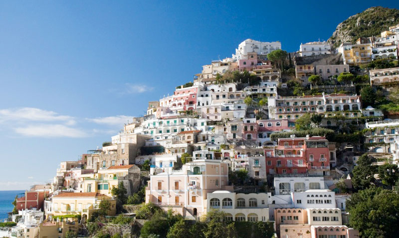 portfolio image- view of the Amalfi coast of Italy, colorful architecture on the hillside with the Mediterranean Sea seen slightly in the background.